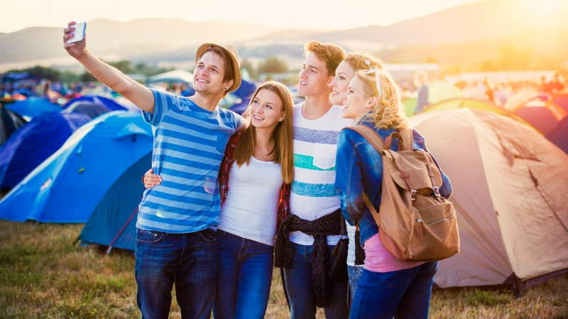 vijf vrienden op festival maken een selfie op de camping